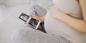 mulher grávida, sentada e segurando uma foto de um ultrassom